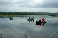 Photo of 3 canoes on very calm lake in Dunner - in background the shore is lined with trees